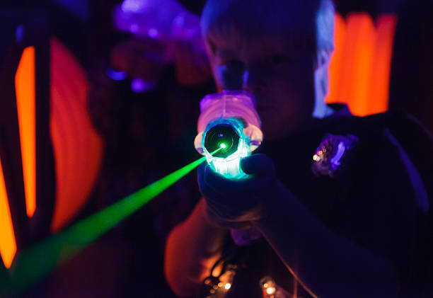 A boy playing laser tag.  Photographed at a high ISO under blacklight to capture true look and feel of the game.